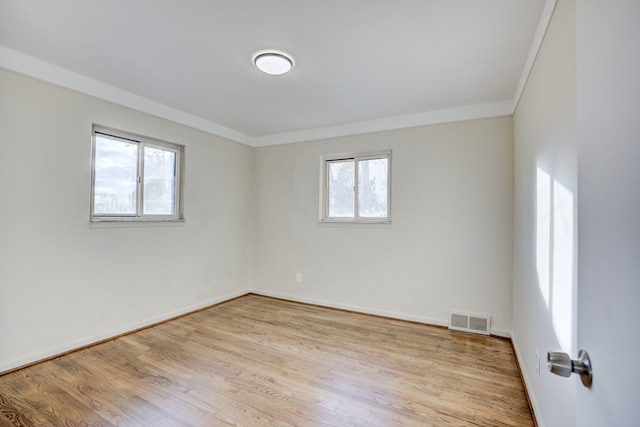 empty room featuring light wood-type flooring, plenty of natural light, and ornamental molding