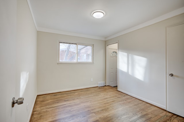 empty room featuring light hardwood / wood-style floors and ornamental molding