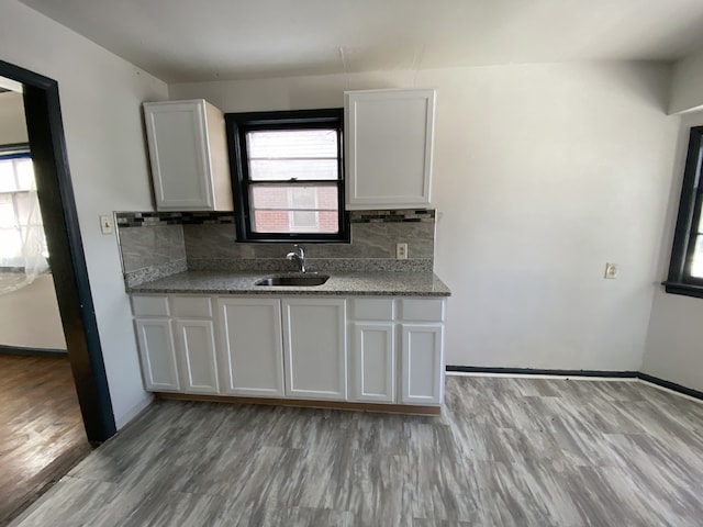 kitchen featuring white cabinets, decorative backsplash, light hardwood / wood-style floors, and sink