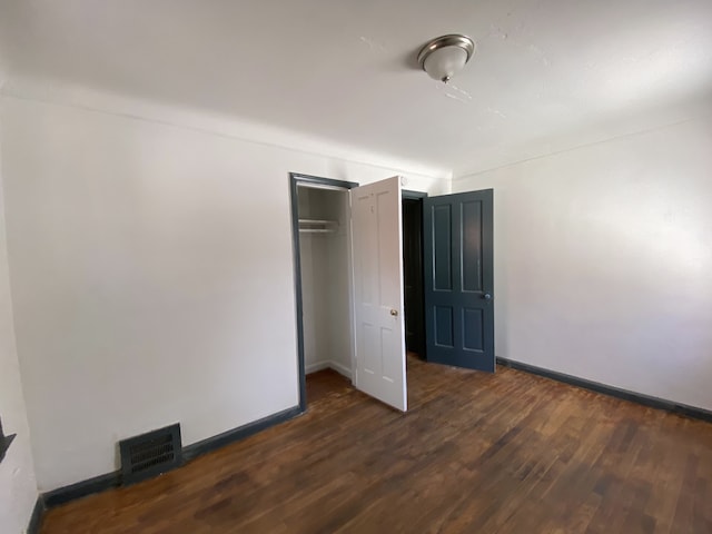 unfurnished bedroom featuring a closet and dark hardwood / wood-style flooring