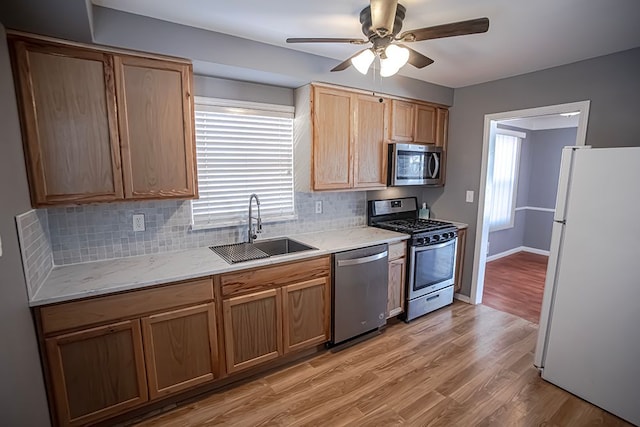 kitchen featuring sink, appliances with stainless steel finishes, ceiling fan, light hardwood / wood-style floors, and decorative backsplash