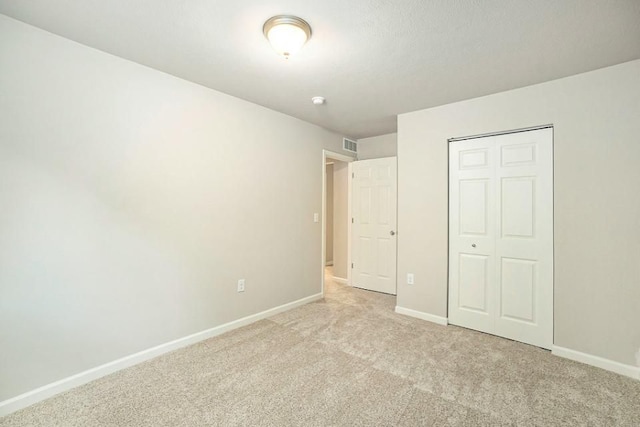 unfurnished bedroom featuring light carpet and a closet