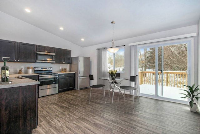 kitchen featuring dark brown cabinetry, stainless steel appliances, dark hardwood / wood-style floors, decorative light fixtures, and vaulted ceiling