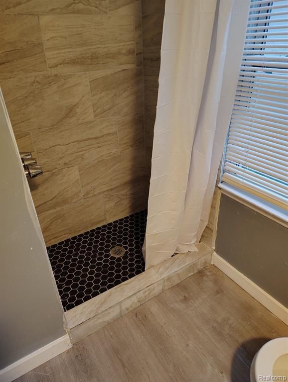 bathroom featuring curtained shower, wood-type flooring, and toilet