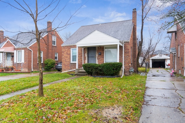 bungalow with a front lawn, an outdoor structure, and a garage