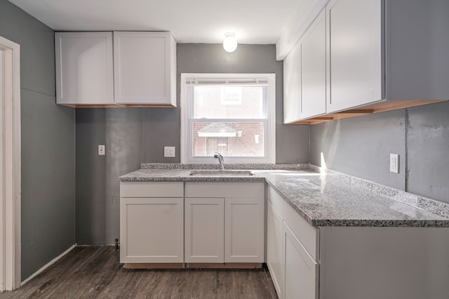 kitchen featuring white cabinets, light stone countertops, dark wood-type flooring, and sink