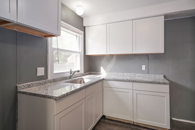 kitchen featuring light stone counters, sink, white cabinets, and dark hardwood / wood-style floors