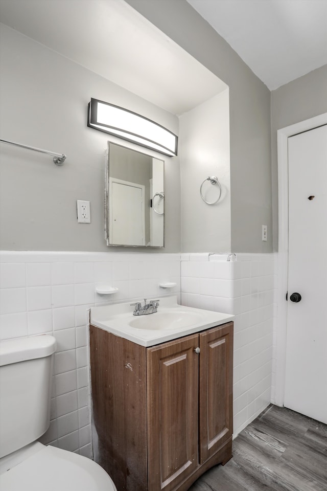 bathroom with hardwood / wood-style floors, vanity, tile walls, and toilet