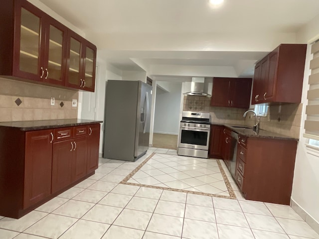 kitchen with sink, wall chimney exhaust hood, stainless steel appliances, tasteful backsplash, and dark stone countertops