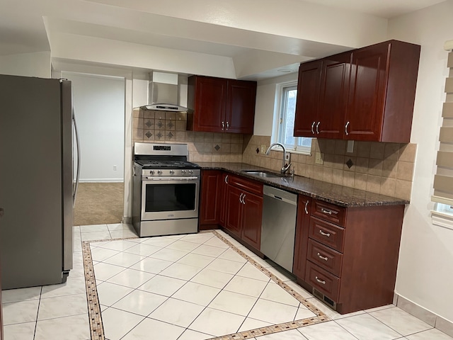 kitchen with dark stone counters, sink, wall chimney exhaust hood, appliances with stainless steel finishes, and tasteful backsplash