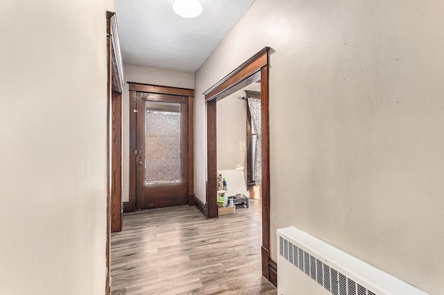 corridor with light wood-type flooring and radiator