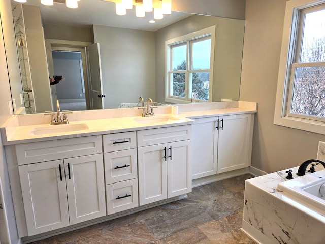 bathroom with plenty of natural light, vanity, and tiled bath