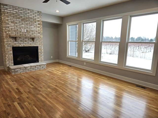 unfurnished living room with a fireplace, light hardwood / wood-style flooring, and ceiling fan