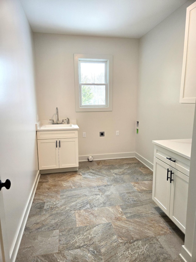 washroom with hookup for an electric dryer, cabinets, and sink