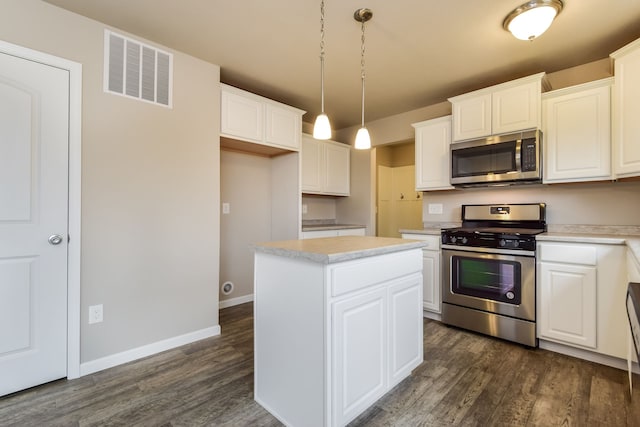 kitchen featuring appliances with stainless steel finishes, decorative light fixtures, white cabinets, dark hardwood / wood-style floors, and a kitchen island