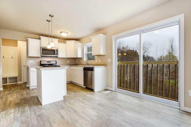 kitchen featuring pendant lighting, a center island, white cabinetry, and stainless steel appliances