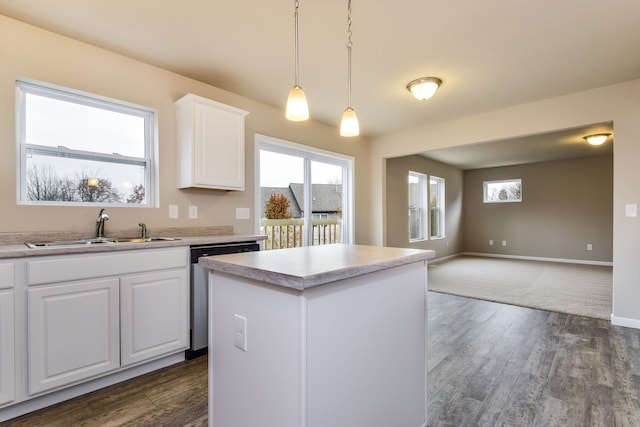 kitchen with white cabinetry, sink, stainless steel dishwasher, decorative light fixtures, and a kitchen island