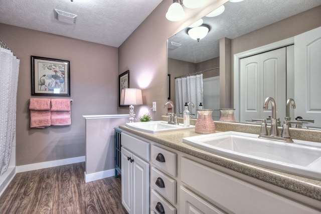 bathroom featuring a shower with curtain, vanity, wood-type flooring, and a textured ceiling