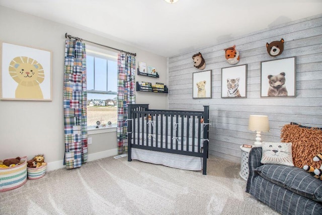 bedroom with carpet floors, a nursery area, and wooden walls