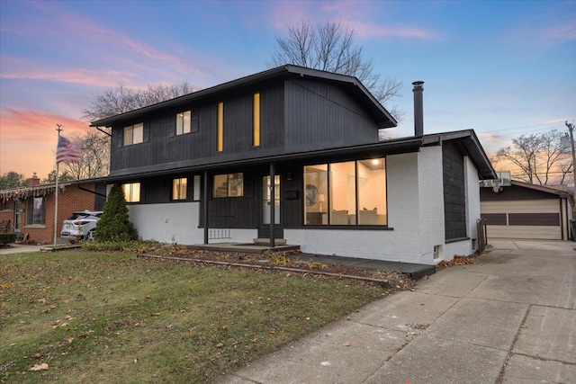 view of front of house with brick siding, covered porch, a front yard, and an outdoor structure