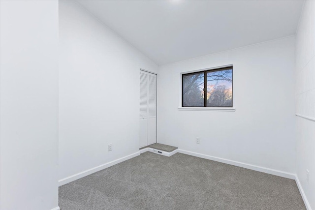 spare room with baseboards, carpet floors, and lofted ceiling