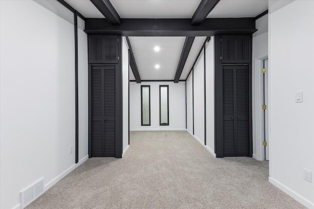 hallway featuring visible vents, beamed ceiling, baseboards, and carpet