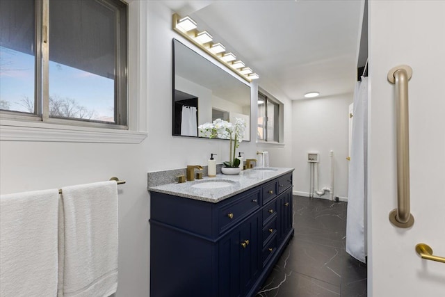 full bathroom featuring double vanity, baseboards, marble finish floor, and a sink