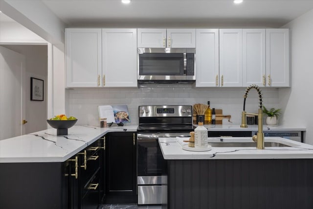 kitchen featuring a sink, backsplash, appliances with stainless steel finishes, and white cabinetry