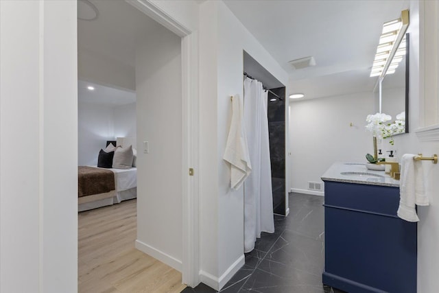 ensuite bathroom featuring vanity, a shower with shower curtain, baseboards, visible vents, and ensuite bathroom