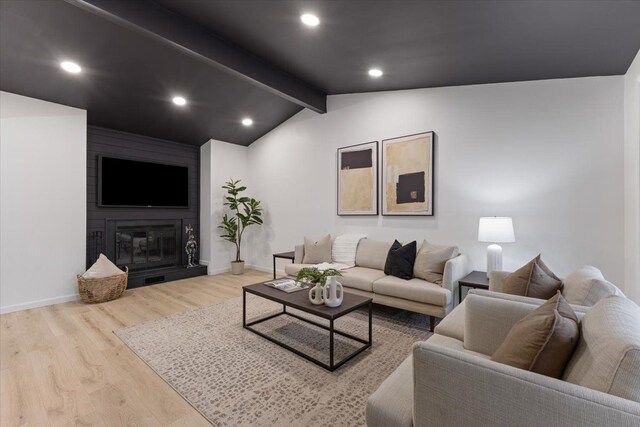 living room with a fireplace, vaulted ceiling with beams, and light hardwood / wood-style floors