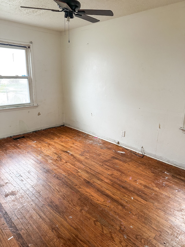 spare room with a textured ceiling, ceiling fan, and dark wood-type flooring