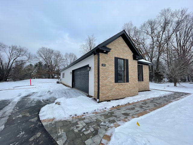 view of snowy exterior featuring a garage