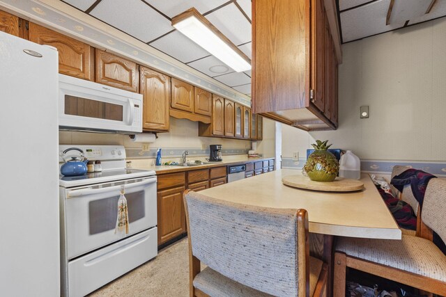 kitchen featuring a drop ceiling, white appliances, and sink