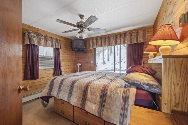 carpeted bedroom featuring baseboard heating, wooden walls, ceiling fan, and cooling unit