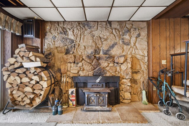 room details featuring a paneled ceiling, wood walls, and a wood stove