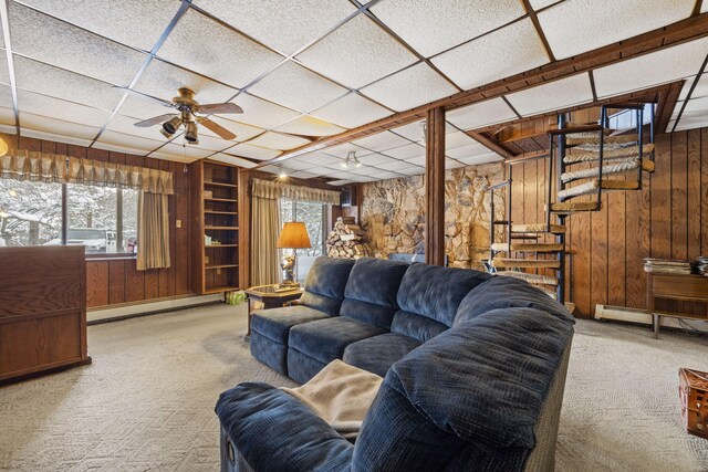 living room with a paneled ceiling, wooden walls, a baseboard radiator, and light carpet