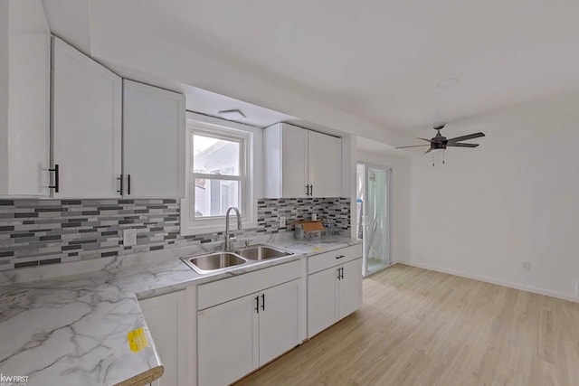 kitchen featuring backsplash, white cabinetry, sink, and light wood-type flooring