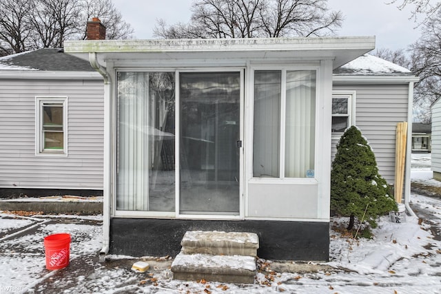 snow covered property featuring a sunroom