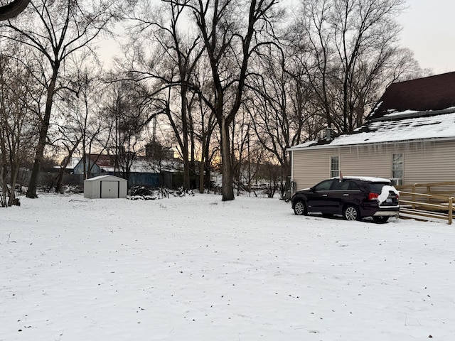 snowy yard featuring a storage shed