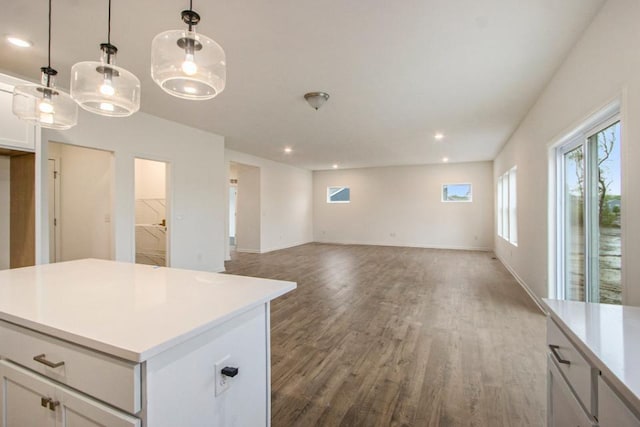 kitchen with a kitchen island, wood finished floors, white cabinetry, light countertops, and pendant lighting