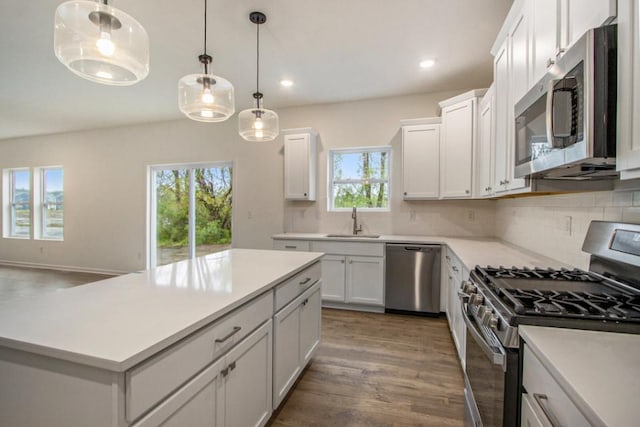 kitchen featuring wood finished floors, a sink, light countertops, appliances with stainless steel finishes, and decorative backsplash