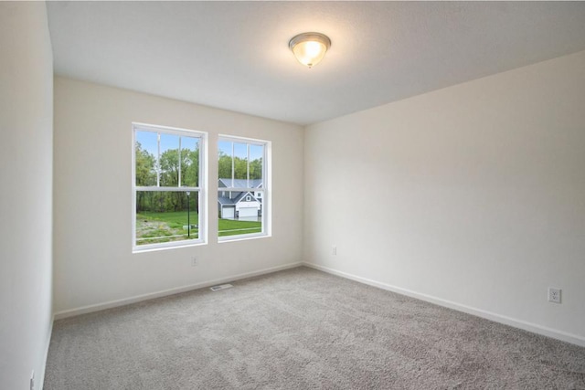 spare room featuring carpet flooring and baseboards