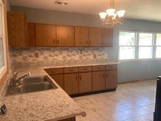 kitchen with pendant lighting, tasteful backsplash, sink, and an inviting chandelier