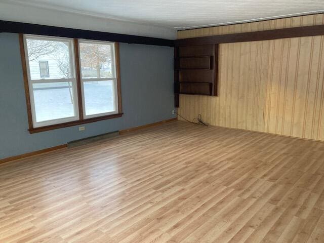 empty room with light hardwood / wood-style floors and wood walls