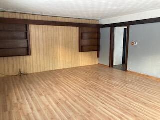 empty room with wooden walls, built in features, and light hardwood / wood-style floors