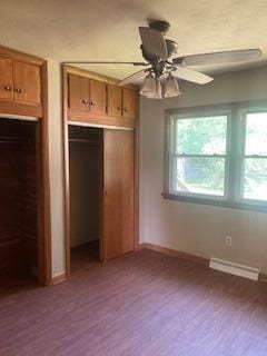 unfurnished bedroom featuring multiple windows, wood-type flooring, and ceiling fan