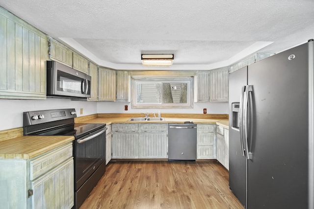 kitchen featuring a textured ceiling, stainless steel appliances, light hardwood / wood-style flooring, and sink