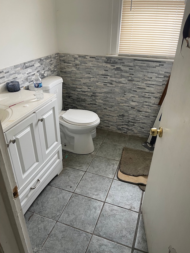 bathroom with tile patterned floors, vanity, toilet, and tile walls