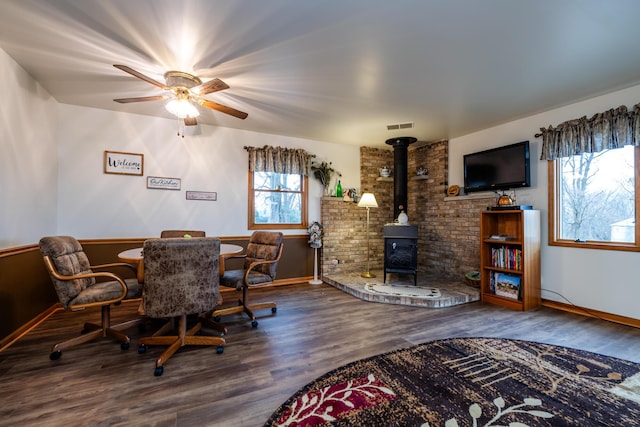 dining space featuring hardwood / wood-style floors, a wood stove, and ceiling fan
