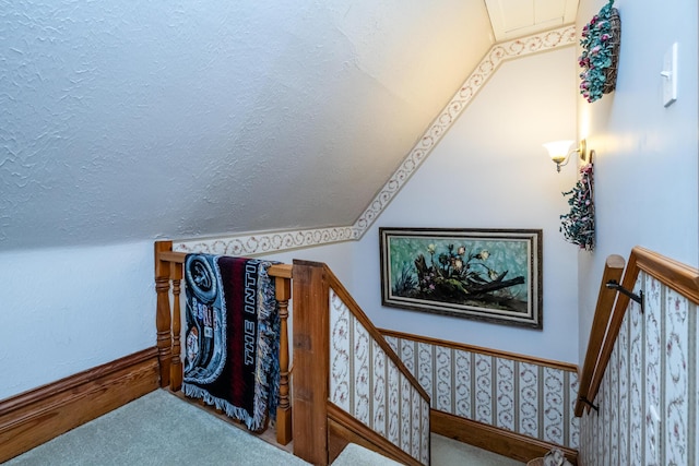 stairway featuring lofted ceiling and carpet floors